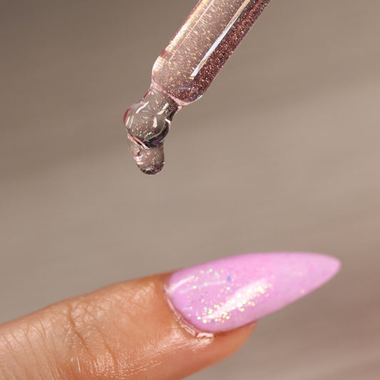Nail glue droplet on a pink glittery nail.