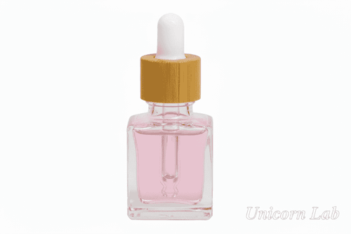 Glass dropper 15ml square bottle with a wooden cap on a white background with pink cuticle oil