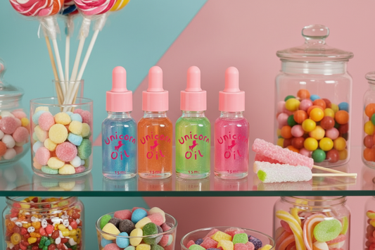 Four bottles of 'Unicorn Oil' with colorful candies on a shelf.