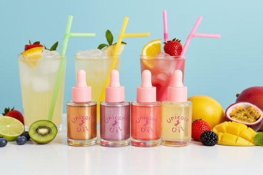 Four bottles of Unicorn Oil with colorful drinks and fruit on a light blue background