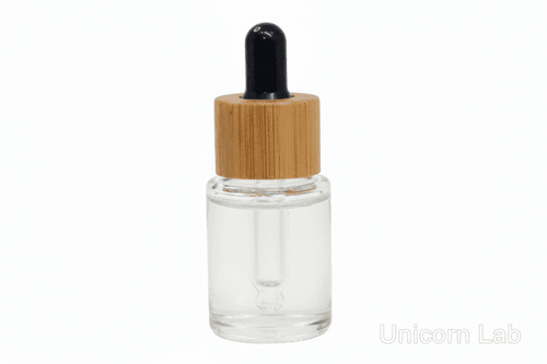 Clear 5ml flat shoulder glass dropper bottle with a bamboo cap on a white background