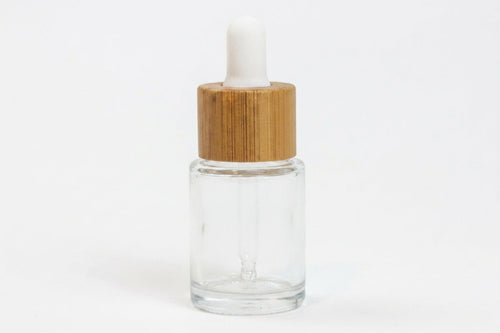 A small clear glass dropper bottle with a light brown bamboo cap and a white rubber bulb, shown on a plain white background.