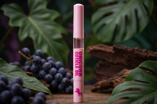 Pink unicorn cuticle oil tube with grapes and leaves in the background