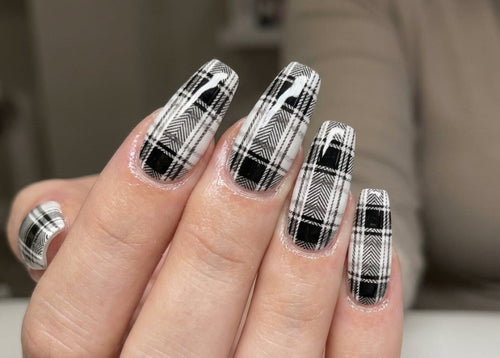 Nail art with black and white plaid design on a neutral background