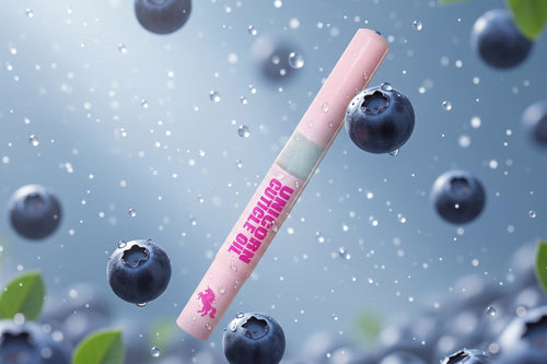 A pink lip gloss tube labeled 'Blueberry Blast' floating among floating blueberries and water droplets against a soft blue background.