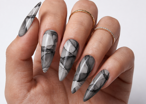 Hand with marbleized gray and black nail design on a light background
