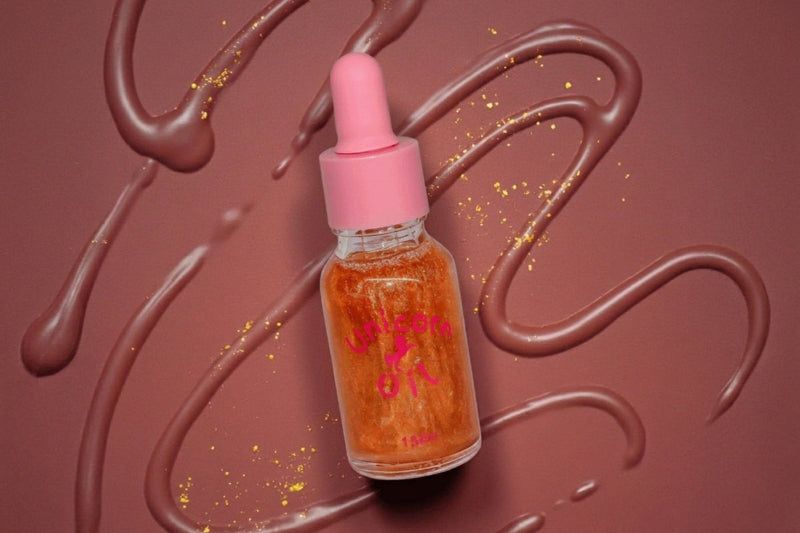 Bottle of chocolate- unicorn cuticle oil with pink cap on a brown background