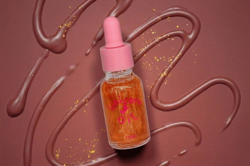 Bottle of chocolate- unicorn cuticle oil with pink cap on a brown background