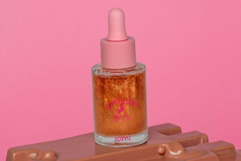 Skincare dropper bottle with pink cap on a pink background. Chocolate scented cuticle oil for salons
