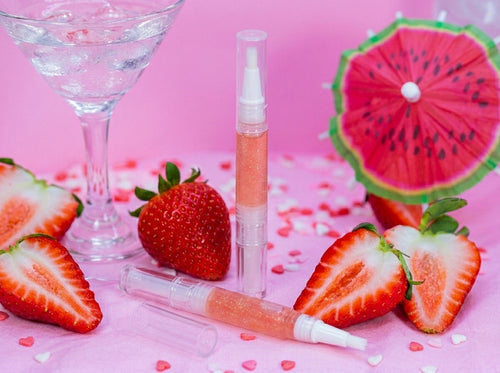 3ml clear strawberry cocktail scented cuticle oil pen surrounded by fresh strawberries. Unicorn cuticle oil collection.