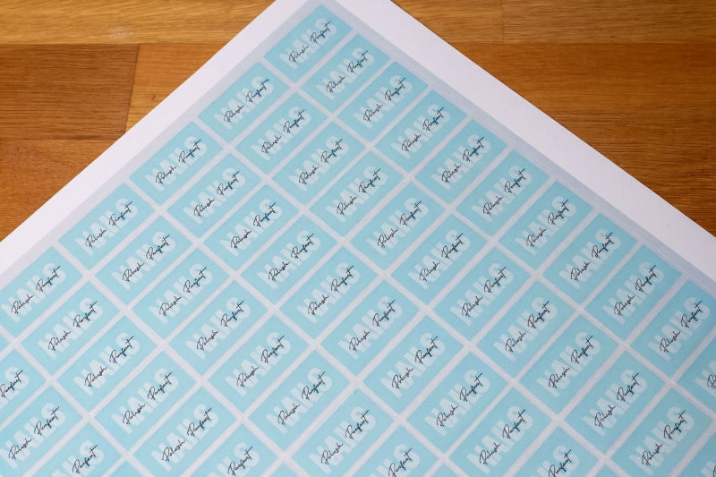Sheet of address labels with a blue background and black text on a wooden surface