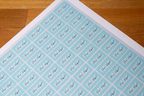 Sheet of address labels with a blue background and black text on a wooden surface