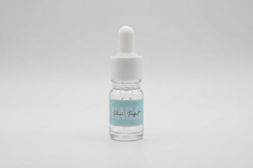 Small glass dropper bottle with a white cap on a light gray background