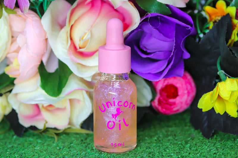 Floral Explosion Unicorn Cuticle Oil 15ml nail serum in a pink dropper bottle with shimmery oil inside. Sitting in front of an arrangement of colourful flowers