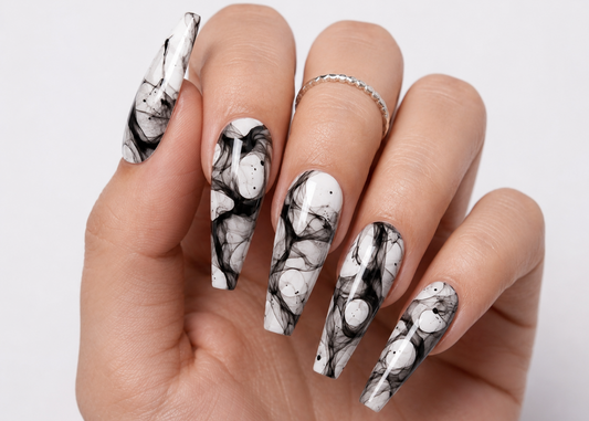 Hand with black and white marble nail design on a light background