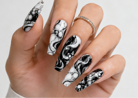 Hand with black and white marble nail design on a light gray background