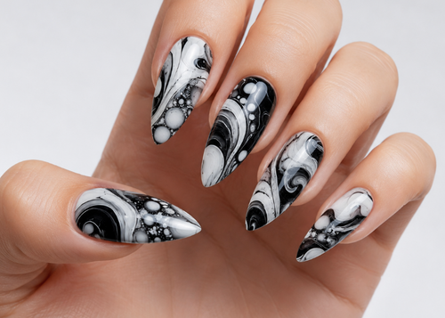 Hand with black and white marble nail art on a light background
