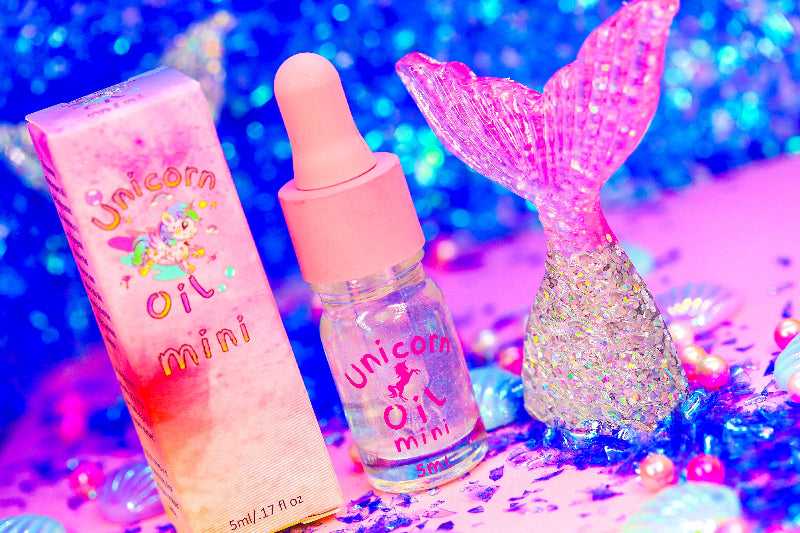 Mermaid Kisses Unicorn Cuticle Oil 5ml mini dropper bottle nail serum with pink lid. Product comes with packaging box shown posing near a mermaid tail charm