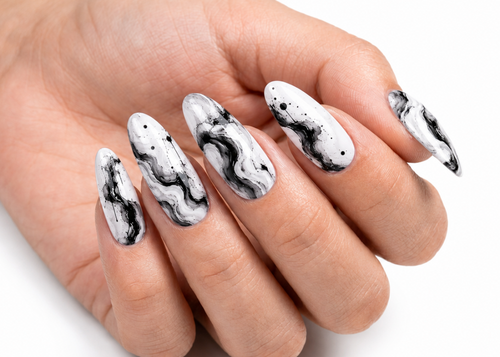 Hand with black and white marbled nail art on a white background