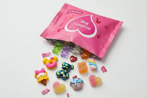 Pink Mystery Charm Bag with assorted colourful nail art charms including gummy bears, donuts, cupcakes, hearts and rainbow designs.