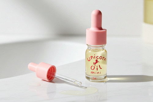 Small bottle labeled 'Unicorn Oil mini' with a pink dropper on a light surface.