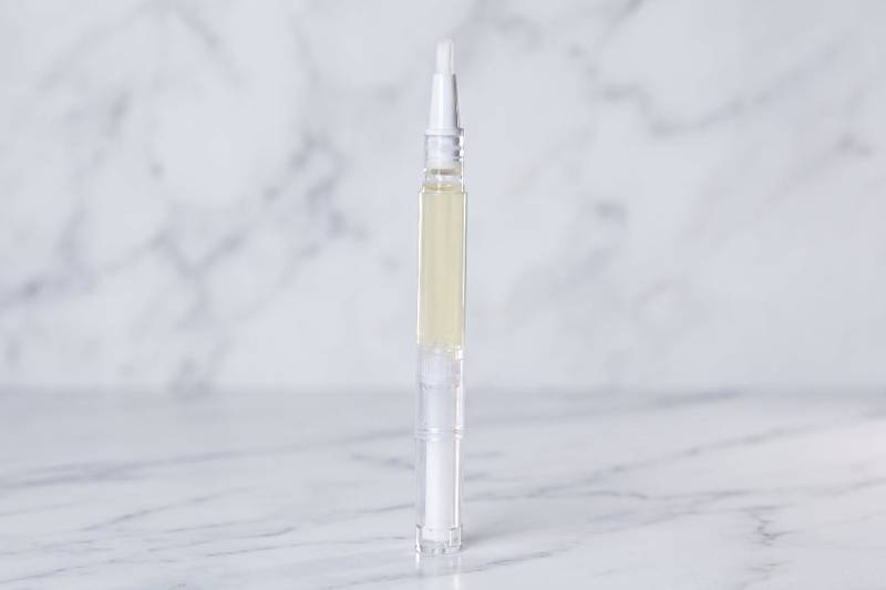 Clear nail serum pen for men on a marble background