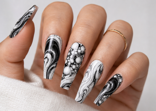 Hand with black and white marble nail art on a neutral background