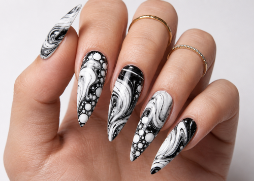 Hand with black and white marbled nail art on a neutral background