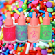 Four bottles of Unicorn Oil cuticle oil in various colors, placed on a background with colorful candies.