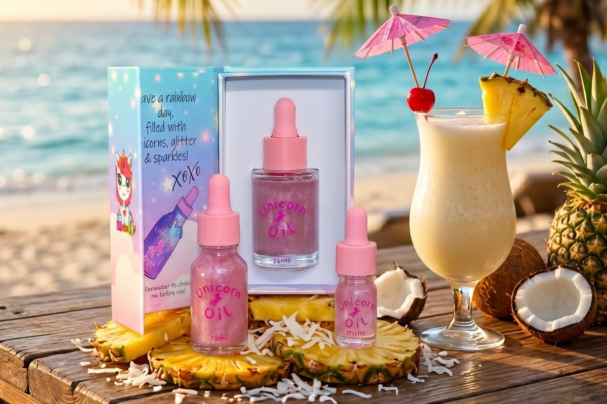 Unicorn oil products with a tropical drink and pineapple on a beach setting