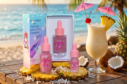 Unicorn oil products with a tropical drink and pineapple on a beach setting