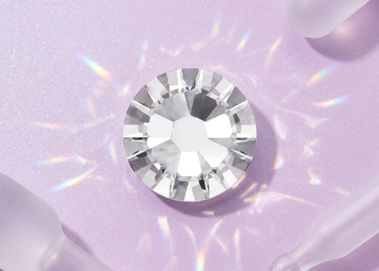 Clear gemstone on a light purple background. SS10 Crystal | Flatback Nail Crystals | Genuine Swarovski 2058 Rhinestones