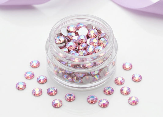 Jar of pink rhinestones with scattered stones on a white background.SS12 Light Rose Shimmer | Flatback Swarovski Crystals | 2088