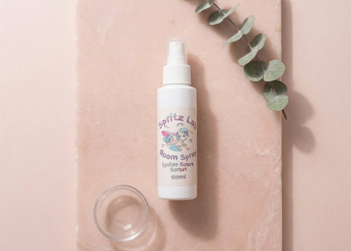 Spritz Luv room spray bottle on a pink surface with eucalyptus leaves