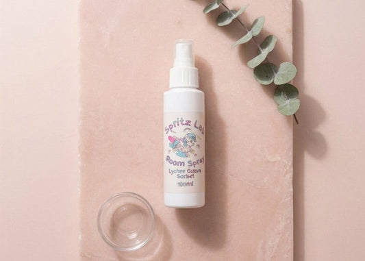 Spritz Luv room spray bottle on a pink surface with eucalyptus leaves