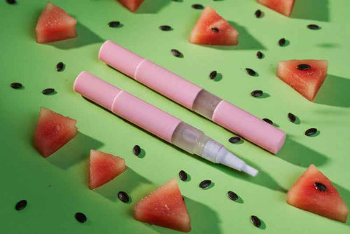 Watermelon scented cuticle oil pen for nail growth, shown with a fresh watermelon slice to highlight the hyper-realistic fragrance of our Australian made vegan nail serum.