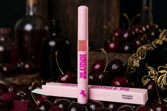 Unicorn Cuticle Oil with packaging on a background of cherries
