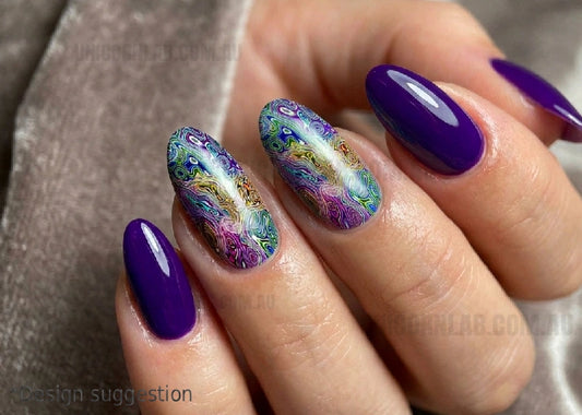 Close-up of a hand with purple and multicolored nail art on a neutral background
