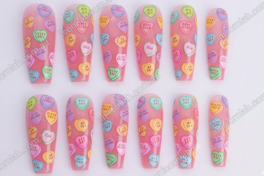 Nail art with colourful heart-shaped candy conversation bubbles on a pink background - Unicorn Lab