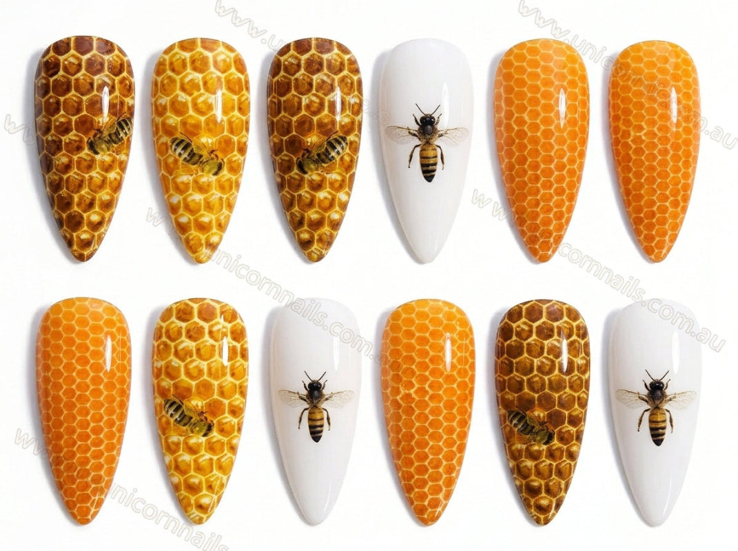 Nail art designs with honeycomb patterns and bees on a white background