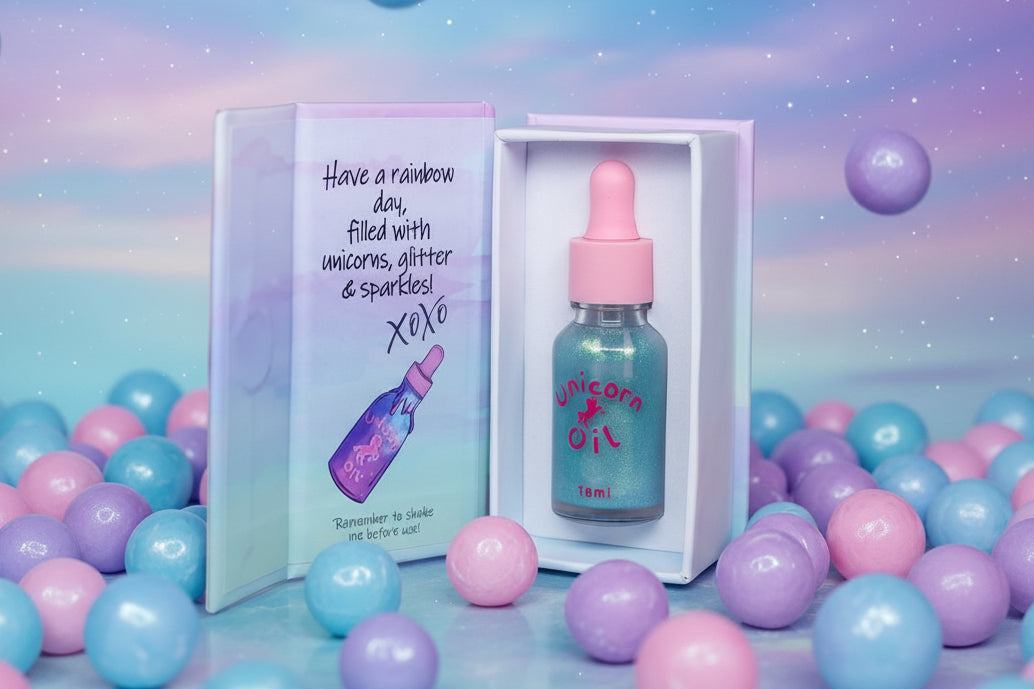 Bubblegum Unicorn Cuticle Oils luxury magnetic close style packaging showing off its signature blue sparkle nail serum inside. Surrounded by bubbles and bubblegum falling. Product is in front of a pastel cloud sky - Unicorn Lab