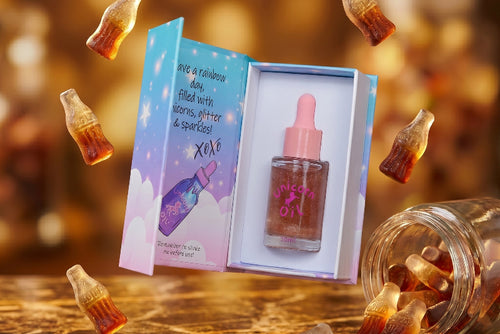 Scented 30ml cuticle oil with dropper and packaging on a reflective surface with scattered bottles. Australian-made candy scented nail serum