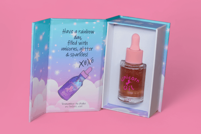 Unicorn oil bottle with dropper in a colorful box on a pink background