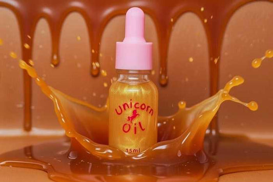 Bottle labeled 'Unicorn Oil' surrounded by splashes of orange liquid against a brown background