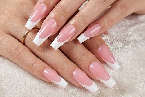 Close-up of hands with pink and white nail polish on a light background