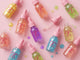 Colorful bottles of 'Unicorn Oil' on a pink background