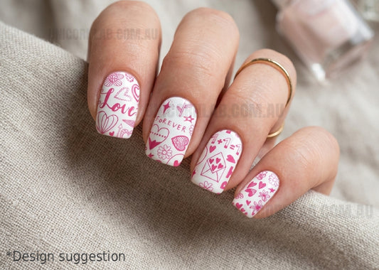 Nails with pink and white heart designs on a beige fabric background