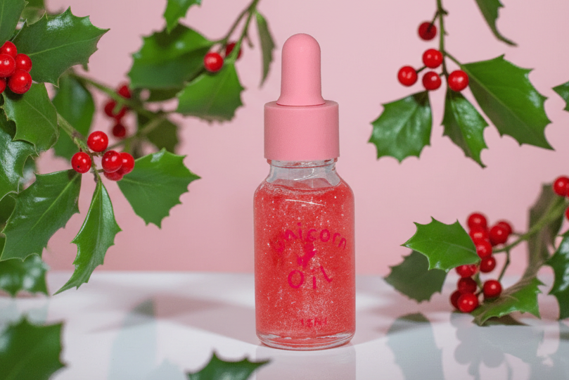 15ml glass dropper bottle of Holly Berry Unicorn Cuticle Oil featuring red shimmering oil and a festive holiday label.