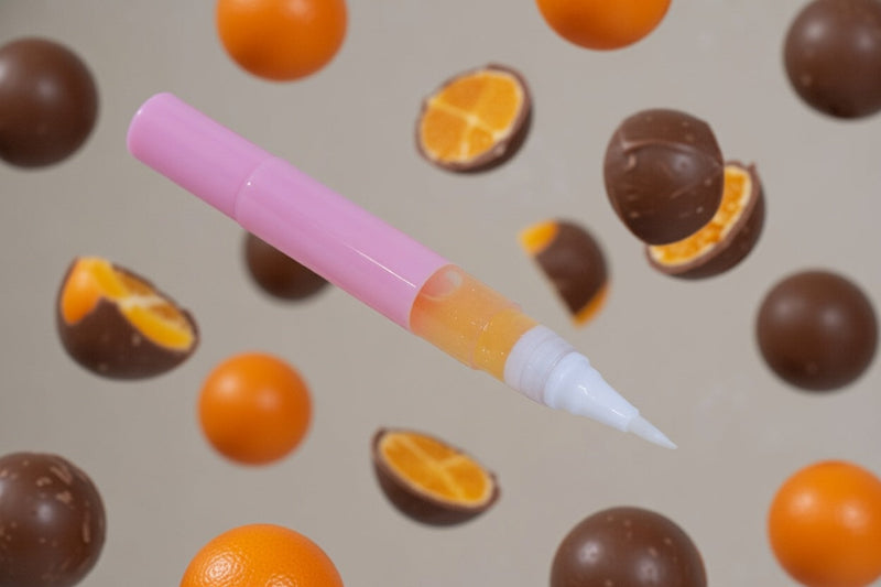 Jaffa Unicorn Cuticle Oil - Unicorn Lab. A pink twist nail serum pen over a choc orange themed backdrop