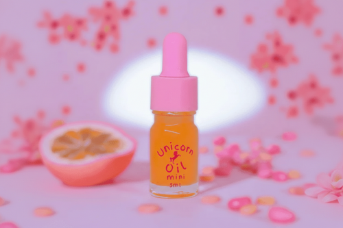 Unicorn oil mini bottle with pink dropper cap for nail care - with a pink background